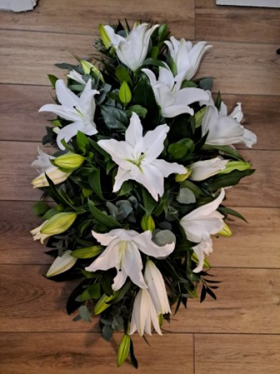 Lily Casket Spray - A blanket of white oriental lillies is beautifully complemented with a selection of foliage.